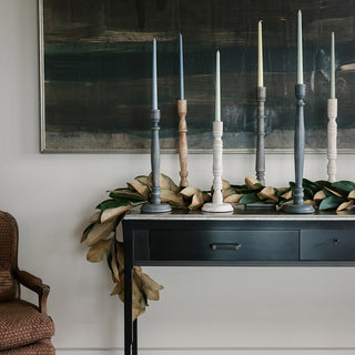 Stylish arrangement of tapered candle holders by CG Hunter in various colors including dark grey wood, enhancing a luxurious living space with modern elegance.