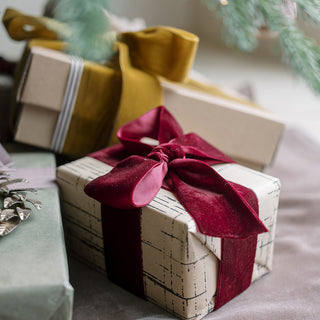 Beautifully wrapped gift adorned with Wide Hand Dyed Velvet Ribbon in Burgundy from CG Hunter, showcasing a festive bow for exquisite holiday decor.
