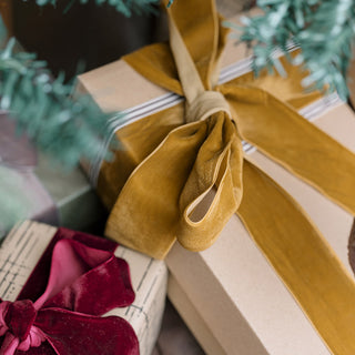 Close-up of a stylishly wrapped gift showcasing exquisite hand dyed velvet ribbon in warm mustard, crafted by CG Hunter, adding a touch of sophistication to any occasion.