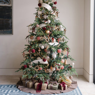 Elegant holiday tree beautifully decorated with the 8’ Natural Wood Bead Garland by CG Hunter, featuring a blend of festive ornaments and gifts beneath.