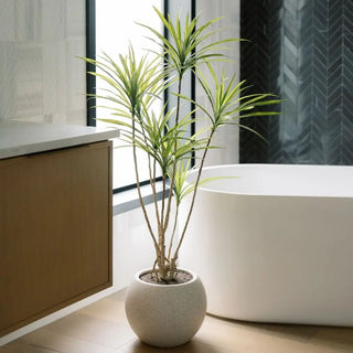 Potted plant in a modern bathroom with a bathtub and wooden cabinet.