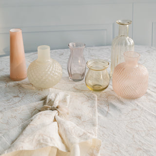 Elegant display of glass vases atop a CG Hunter Blush Lilies Tablecloth, paired with matching napkin, creating a luxurious dining ambiance.