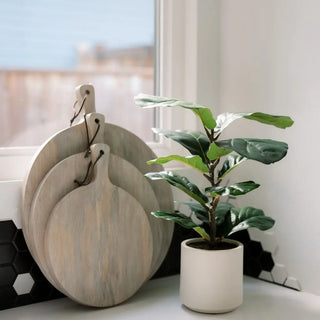 Set of wooden cutting boards and a potted plant on a windowsill.