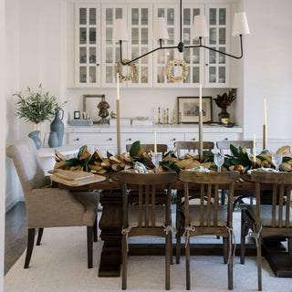 Elegant dining setup featuring the 9' Faux Green Magnolia Leaf Garland by CG Hunter, beautifully arranged on a rustic wooden table, enhancing the sophisticated ambiance of the room.