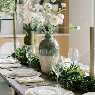 Elegant dining table setting with a vase of flowers and greenery.