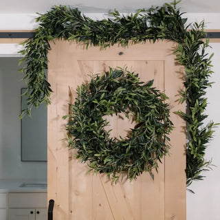 Green wreath and garland on a wooden door with a neutral background