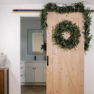 Wooden sliding door with a wreath and greenery in a modern interior setting