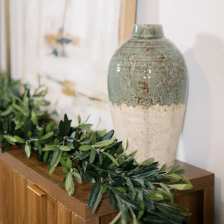 Decorative vase on a wooden surface with greenery