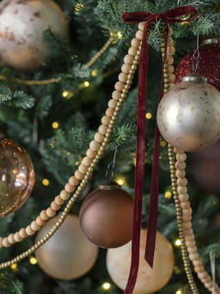 Decorative Mercury Marble Glass Ornaments by CG Hunter beautifully adorning a lush Christmas tree, featuring elegant marbled and latte tones, creating a luxurious festive atmosphere.