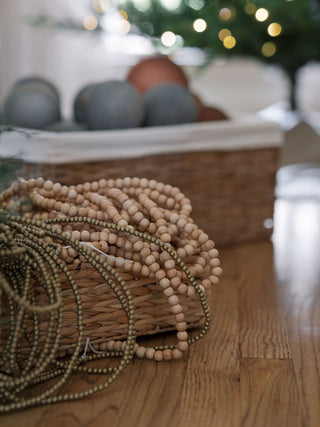 Natural Wood Handmade Bead Garland on Spool by CG Hunter, elegantly arranged with a basket, perfect for enhancing holiday décor.