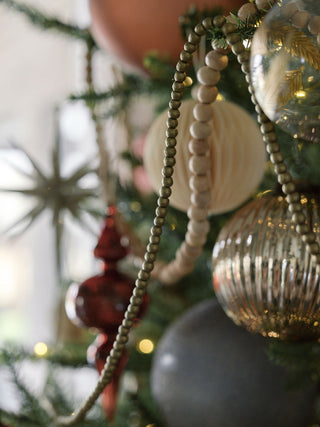 Natural Wood Handmade Bead Garland on Spool by CG Hunter, beautifully draped on a decorated Christmas tree, adding luxury to holiday decor.
