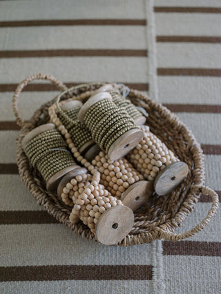Elegant display of natural wood handmade bead garlands on spools, perfect for festive styling, by CG Hunter.
