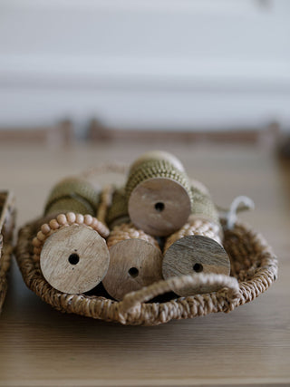 Sophisticated assortment of natural wood and decorative bead spools in a woven basket by CG Hunter for festive decoration.