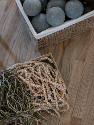 Artfully arranged natural wood and decorative bead garlands displayed in baskets, showcasing holiday elegance by CG Hunter.
