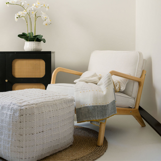Stylish living space featuring CG Hunter Square Striped Woven Ottoman Pouf paired with modern chair and decor accents for an elegant atmosphere.