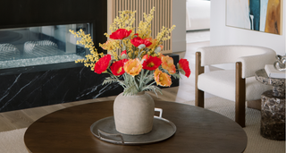 Decorative flower arrangement in a vase on a coffee table in a living room.