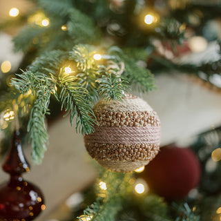 A stunning pink and natural colored jute ornament from the Natural Jute Wrapped Christmas Ornaments by CG Hunter, elegantly hanging among festive decorations on a Christmas tree.