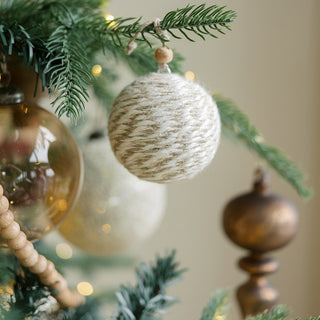 A close-up shot of a handcrafted jute ornament from the Natural Jute Wrapped Christmas Ornaments collection by CG Hunter, showcasing its unique texture and earthy colors adorning a festive tree.