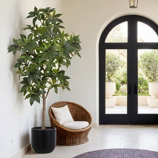 Stylish interior setup featuring the 7' Faux Potted Money Tree by CG Hunter alongside a wicker chair and modern door, creating a warm and inviting atmosphere.