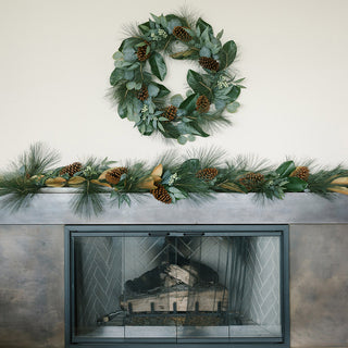 Elegant setting featuring the Magnolia, Eucalyptus, Pinecone, & Needle Pine Wreath and Garland by CG Hunter above a stylish fireplace, enhancing seasonal decor.