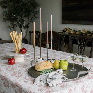 A beautifully arranged table featuring the Charlotte Serving Pedestal by CG Hunter, adorned with fresh fruits, candles, and a loaf of bread, embodying a luxurious dining experience.