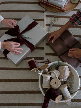 Craftspeople wrapping gifts with luxurious hand-dyed velvet ribbons, adding a refined touch to seasonal celebrations. By CG Hunter – Hand Dyed Velvet Ribbon 10 Yards Per Spool.