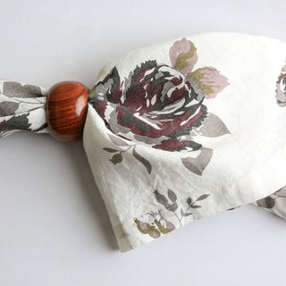 Tastefully knotted CG Hunter Eggplant and Grey Roses Napkin with a wooden ring, emphasizing sophistication and luxury for any table decor.