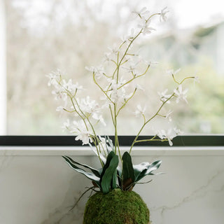 Artificial plant with white flowers and green leaves on a marble surface