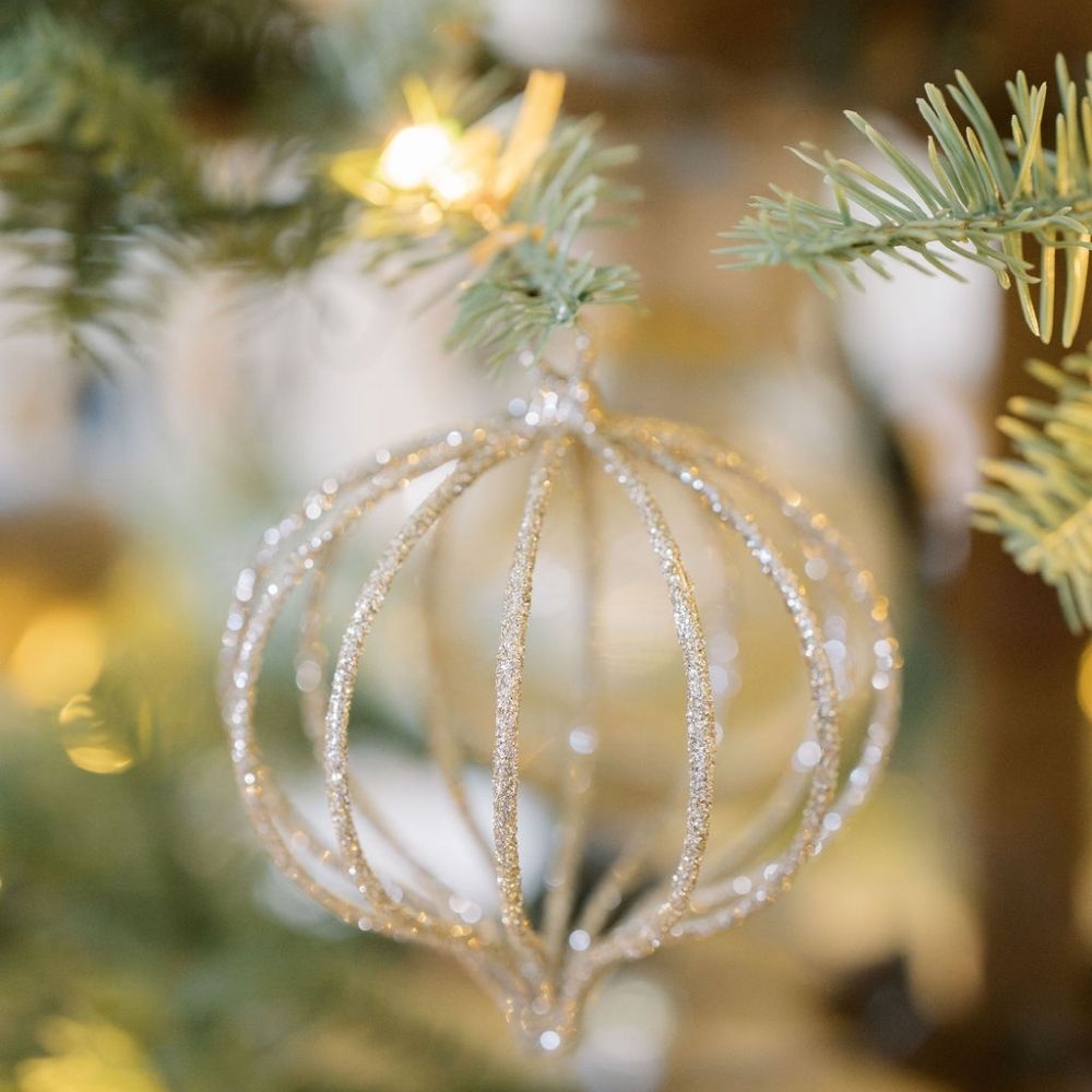 4" Champagne Assorted Ornament by CG Hunter, elegantly shimmering wire onion sphere ornament glistening amidst holiday lights on a beautifully decorated tree.