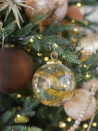 Charming 3" Artisan Glass Gold Etched Leaf Ornament by CG Hunter, delicately hanging among twinkling lights and holiday decor on a lush Christmas tree.