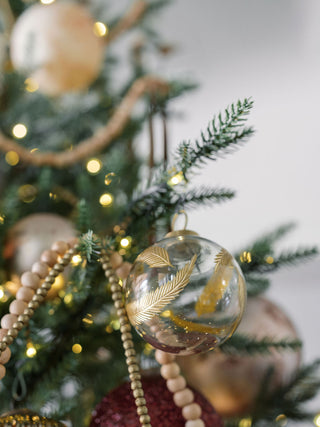 4" Artisan Glass Gold Etched Leaf Ornament by CG Hunter, beautifully showcased on a festive Christmas tree adorned with warm lights.