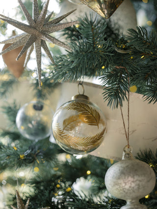 4" Artisan Glass Gold Etched Leaf Ornament by CG Hunter, highlighted amongst sparkling decorations on a shimmering holiday tree.