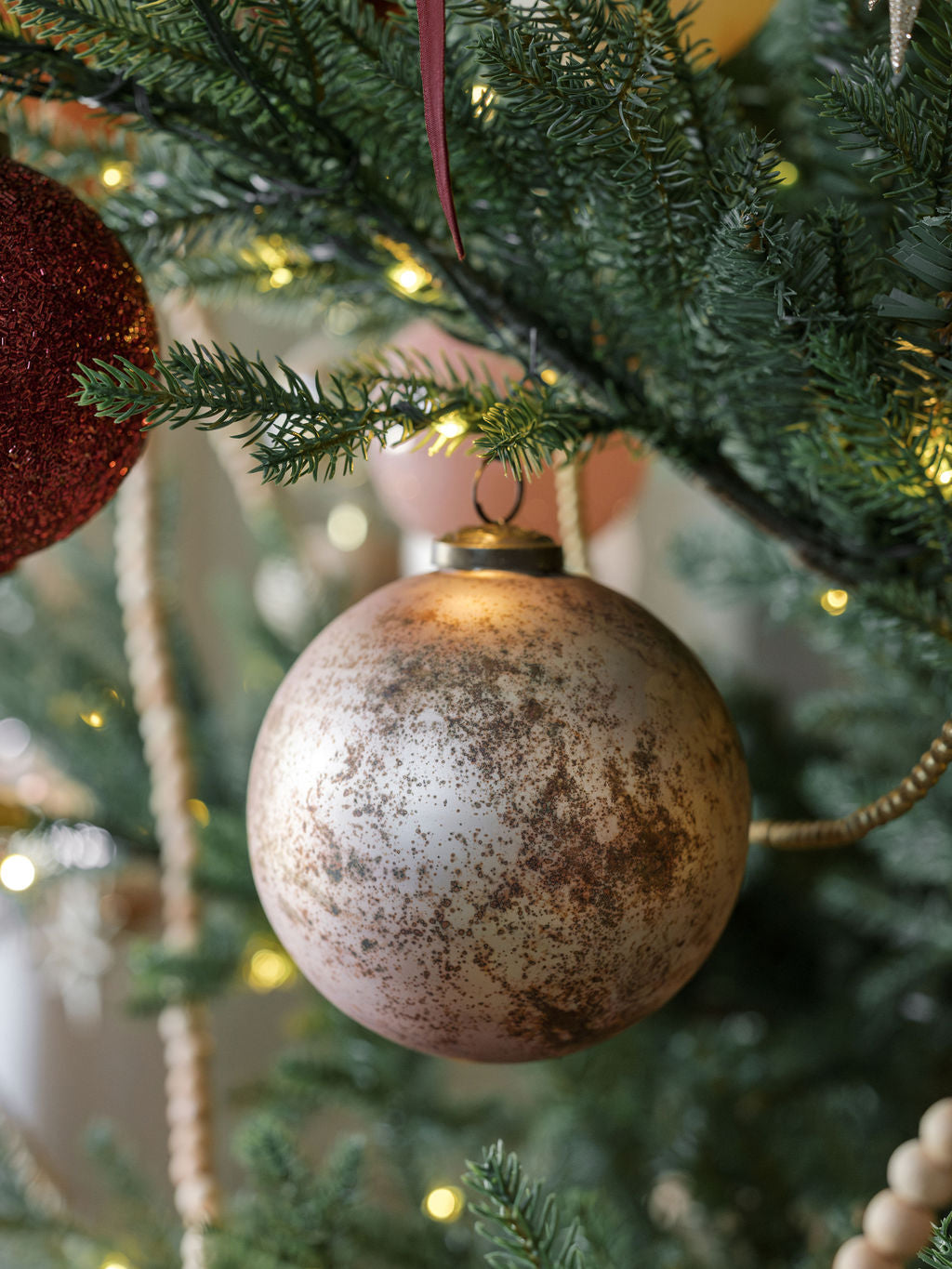 closeup of Handcrafted Mouthblown 5-inch Mercury Glass Ornaments in latte on a timeless tree.