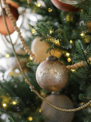 Chic 3-inch Mercury Marble Glass Ornament by CG Hunter, captured amidst a beautifully adorned Christmas tree, featuring a chic marbled design and bronze accent.