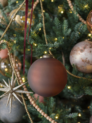 Elegant 5" Frosted Cinnamon Glass Ornament by CG Hunter, beautifully displayed on a festive Christmas tree surrounded by warm lights and decorative elements.