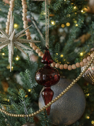 Striking Bordeaux glass finial ornament by CG Hunter amidst a lush holiday tree, adding a touch of elegance and vintage style to holiday decor.