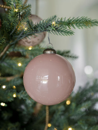 A captivating glossy vintage rose glass ornament, 4 inches in size, gracefully suspended from a Christmas tree branch, from the luxury collection by CG Hunter.