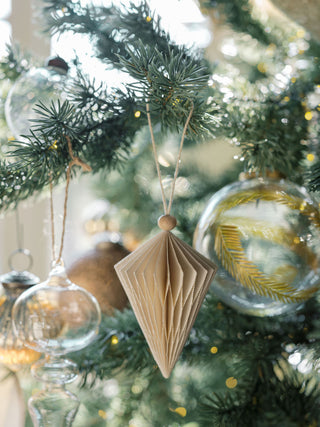 Elegant hand-cut paper ornament from CG Hunter, featuring a finely detailed diamond shape, gracefully hanging on a beautifully adorned Christmas tree.