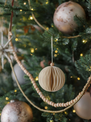 Stylish hand-cut paper ornament from CG Hunter, showcasing a round design, delicately suspended amidst festive decorations on a glamorous Christmas tree.