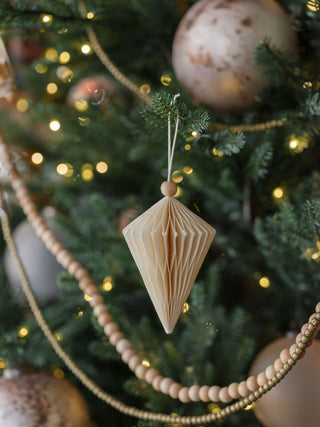 Refined hand-cut paper ornament from CG Hunter, designed in a diamond shape, elegantly displayed on a beautifully decorated Christmas tree with twinkling lights.