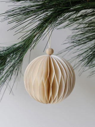Elegant hand-cut paper ornament by CG Hunter, featuring a stunning honeycomb design, gracefully suspended from a pine bough, perfect for enhancing your Christmas tree's festive charm.