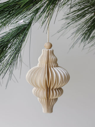 Beautifully crafted hand-cut paper ornament by CG Hunter, presenting an intricate layered design, elegantly adorning a pine tree, an exquisite addition to your festive celebrations.
