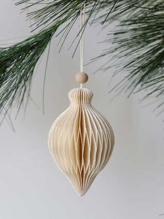 Luxurious hand-cut paper ornament by CG Hunter, showcasing a classic teardrop shape, delicately hanging among pine branches, adding a touch of sophistication to your holiday decor.