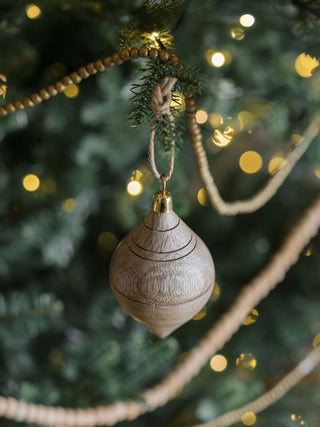 Stylish Natural Mango Wood Ornament by CG Hunter adorned with intricate lines, suspended from a tree branch, embodying a blend of tradition and elegance.