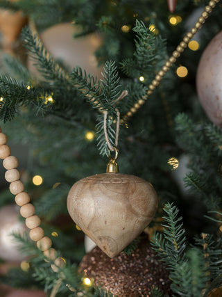 Luxurious hand-carved natural mango wood ornament by CG Hunter, elegantly hanging on a Christmas tree with a jute hanger.