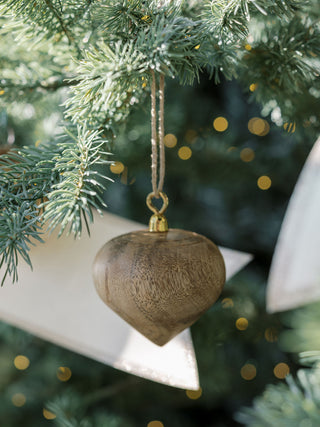 Beautiful close-up of a natural mango wood heart ornament by CG Hunter, showcasing its exquisite craftsmanship and ideal for enhancing festive decor.