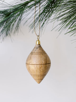 Artistic natural mango wood ornament by CG Hunter, showcasing intricate craftsmanship with striped details, beautifully poised amidst green pine.
