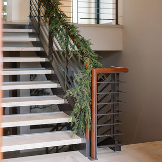 Sophisticated 9' Artificial Pine Garland with Pinecones by CG Hunter, artistically arranged along a contemporary staircase, exuding luxury and charm.