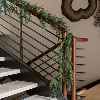 Chic 9' Artificial Pine Garland with Pinecones by CG Hunter, gracefully cascading over a stylish staircase, perfect for timeless holiday elegance.