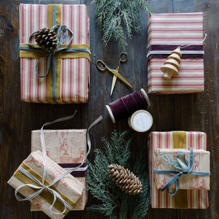 A beautifully wrapped assortment of holiday gifts featuring luxurious stripes and rich tones, embellished with CG Hunter's hand dyed velvet ribbon, perfect for elegant gift presentation.